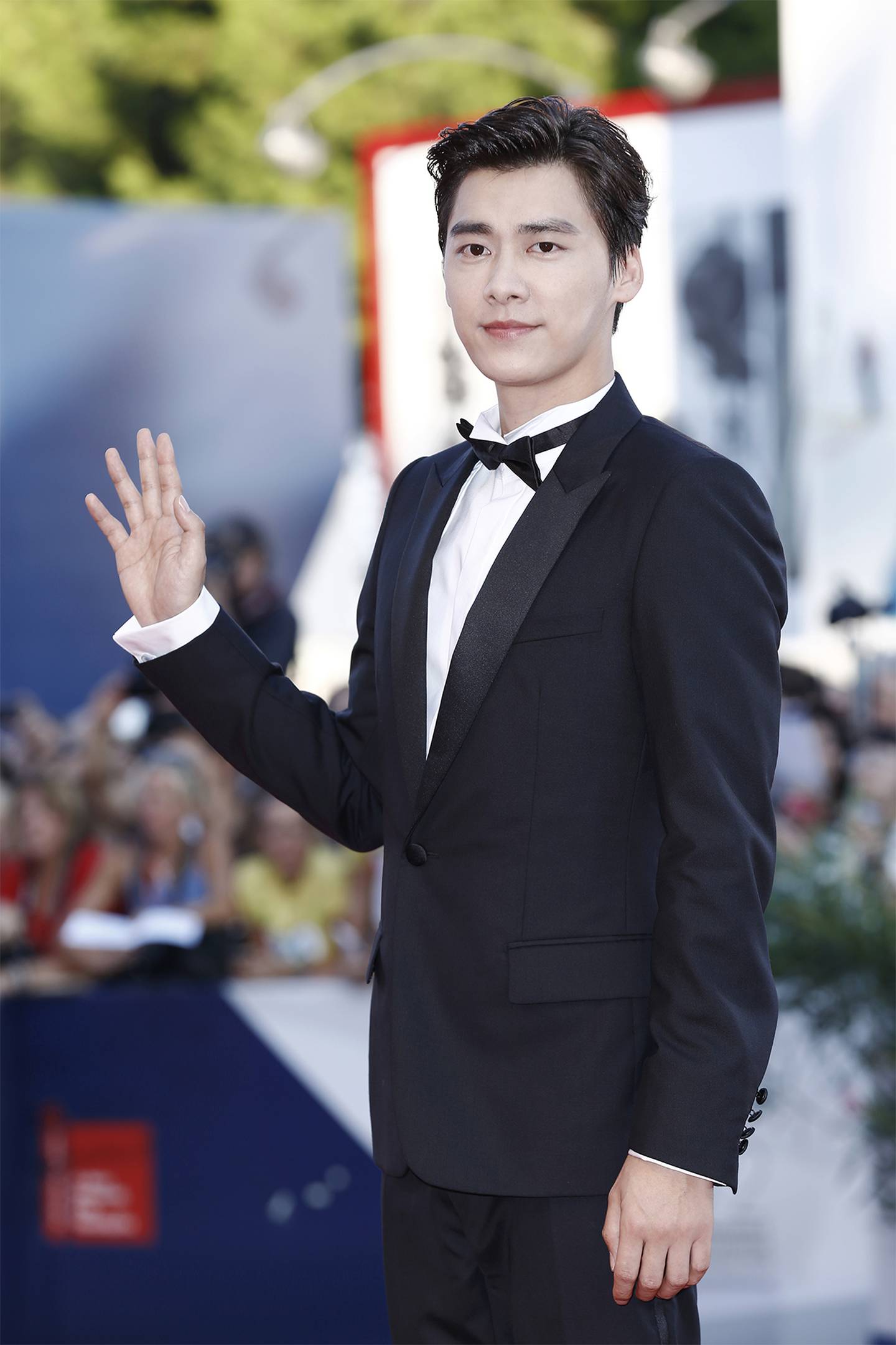 Actor Li Yifeng wearing a black tuxedo at a premiere red carpet event.