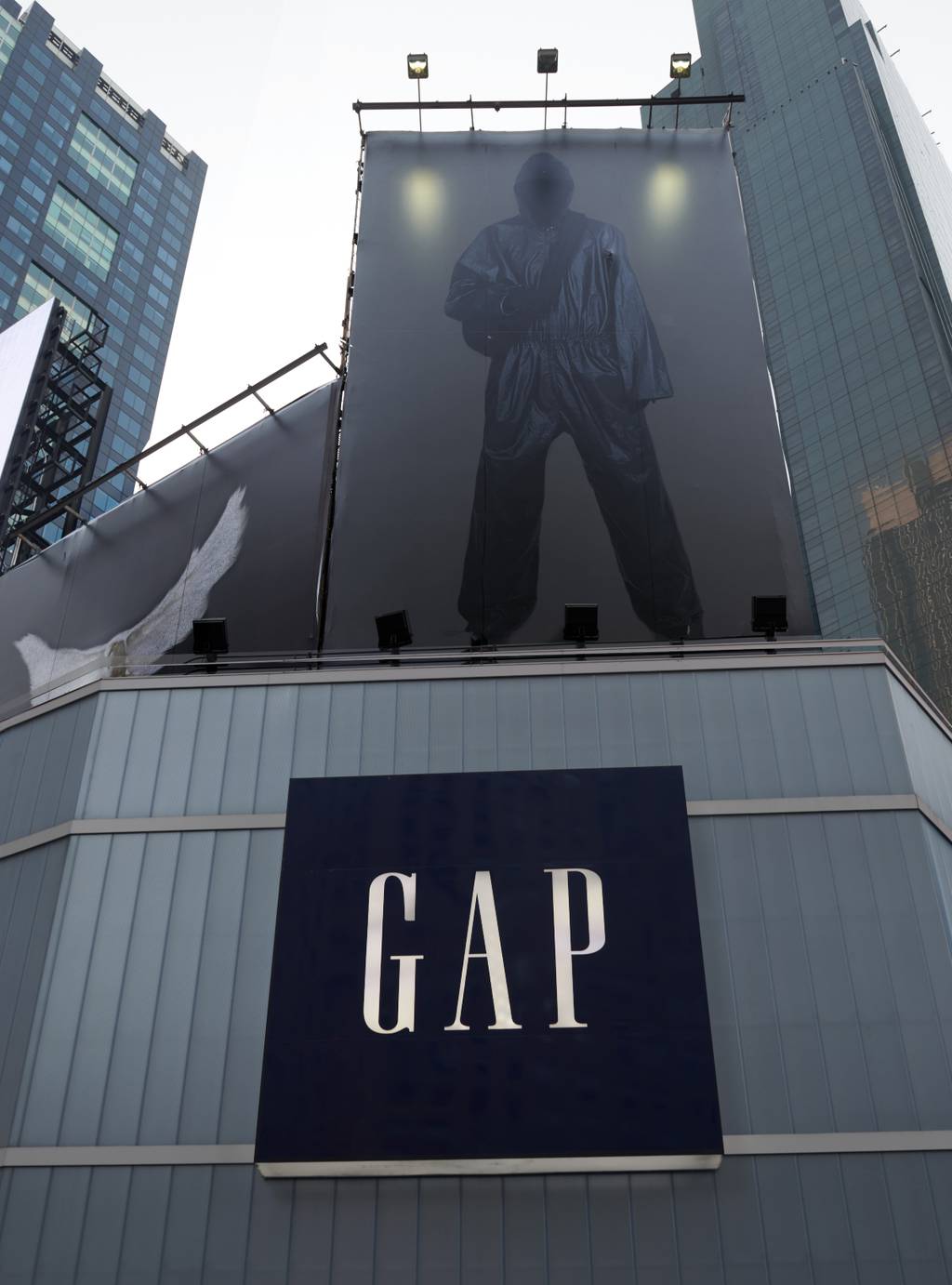 A billboard of a figure dressed in all black with his face covered in a black mask sits poised above the Gap logo at its Times Square store.